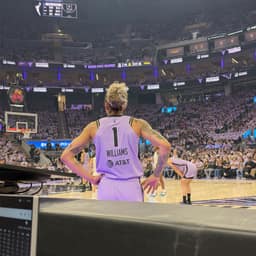 Courtside view of a basketball player in a lavender number 1 jersey with Williams on the back, standing with hands on hips in a packed arena.