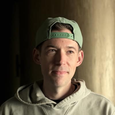 Portrait of Brendan Irvine-Broque wearing a backward green cap and green hoodie.