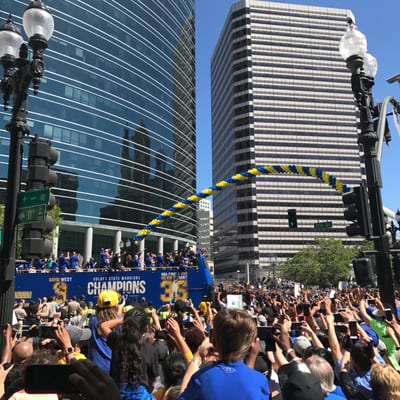 A crowd of fans gathers around a blue parade bus celebrating the Golden