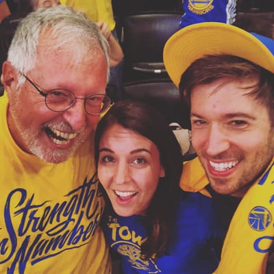 Three smiling people pose for a selfie at a Golden State Warriors