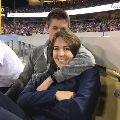 A couple sits close together in stadium seats at a baseball game, with the
