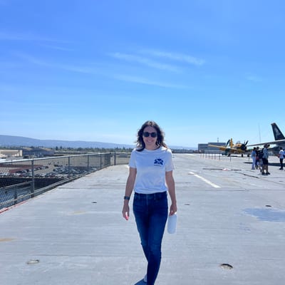 A woman in a white t-shirt and jeans walks along an airport runway or
