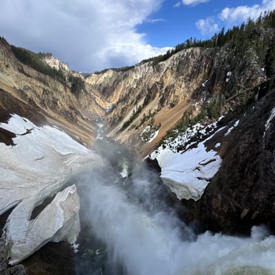 A powerful waterfall cascades down through a dramatic rocky canyon with
