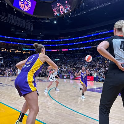 A WNBA basketball game in progress at a packed arena, with players in