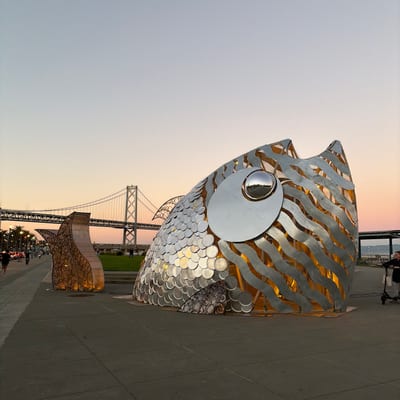 A large metallic fish sculpture with reflective scales and a circular eye