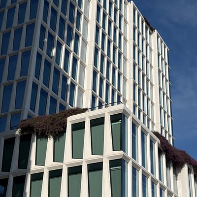 A modern white office building with a geometric glass facade features