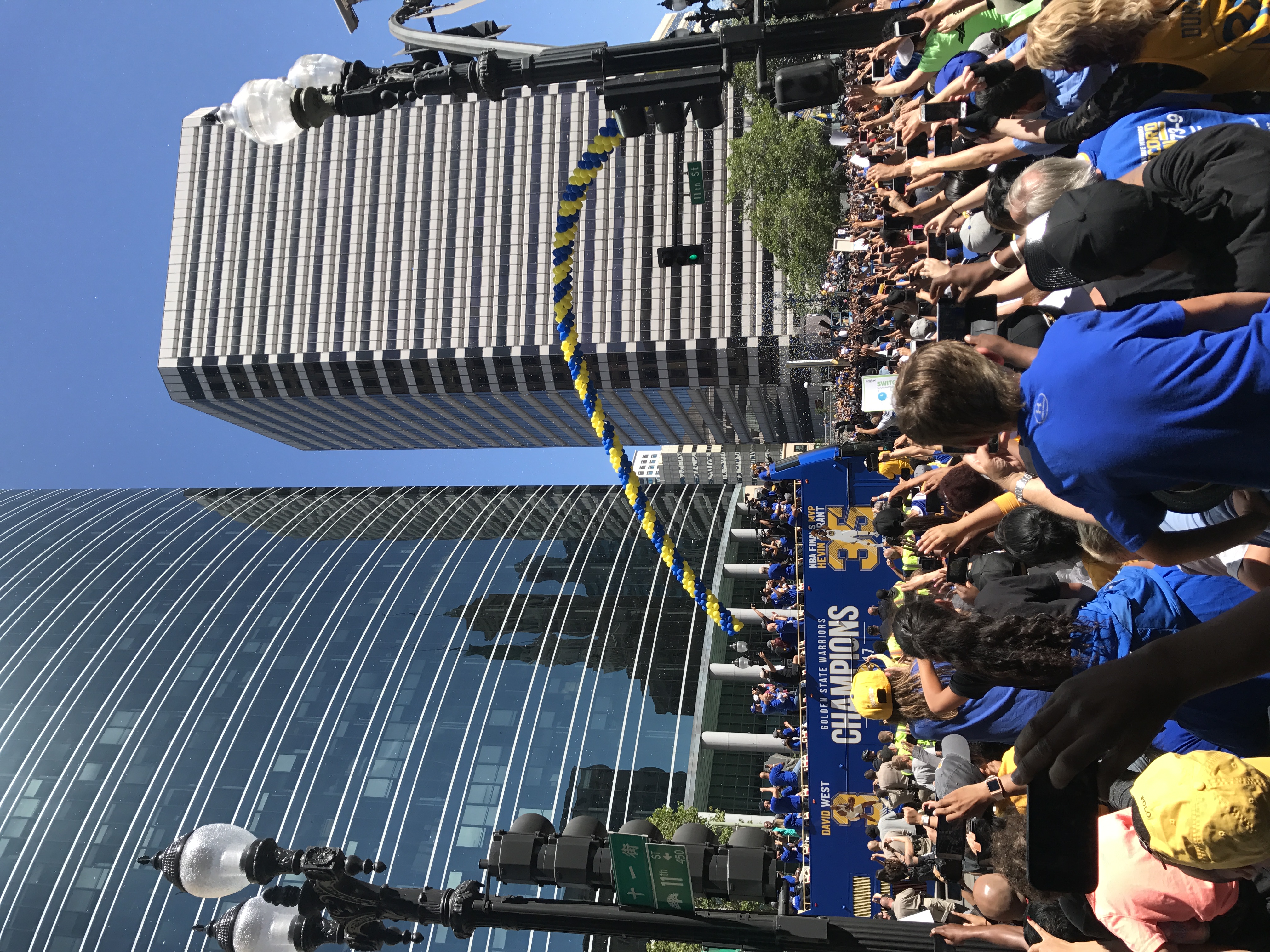 A crowd of fans gathers around a blue parade bus celebrating the Golden