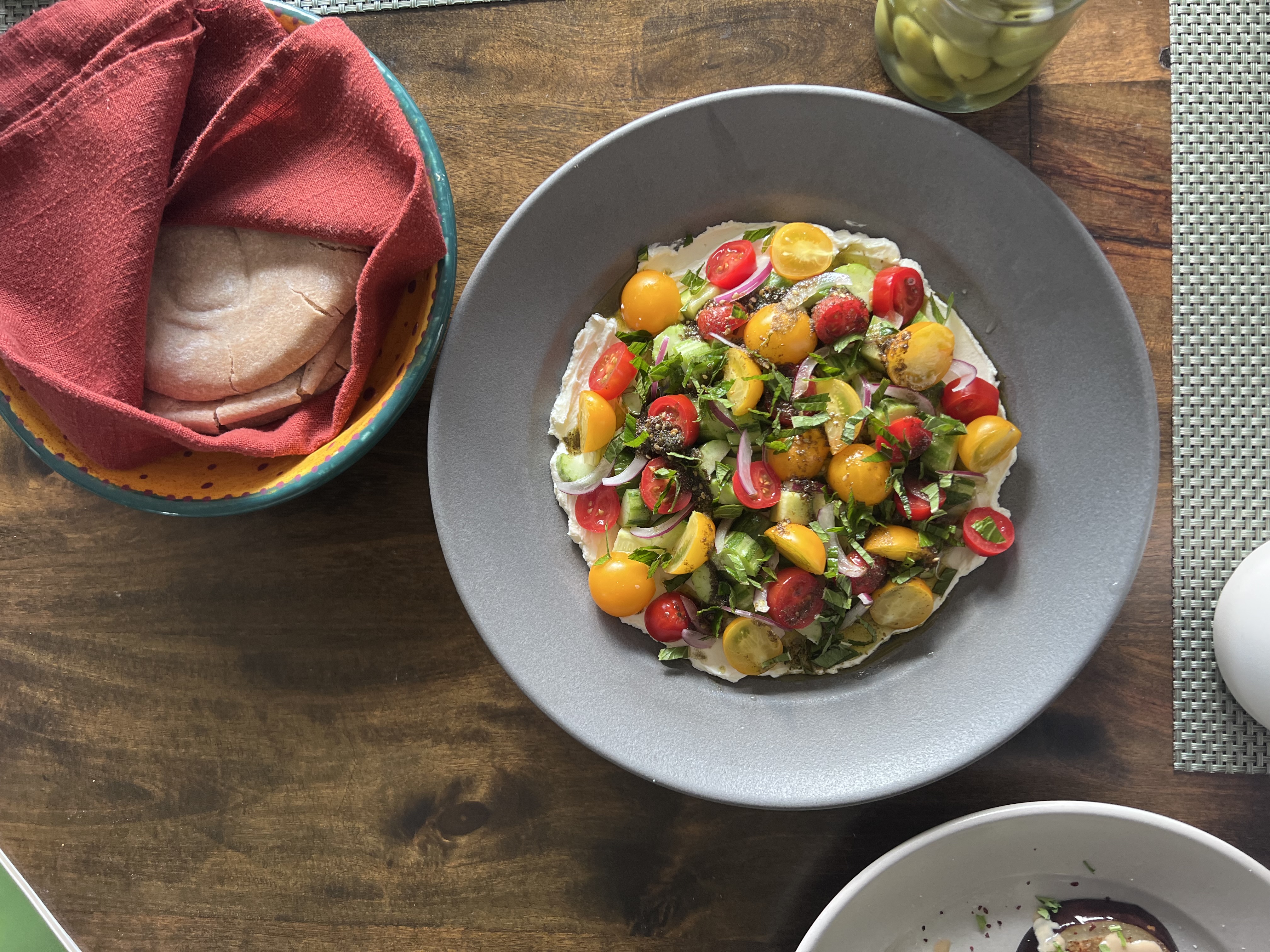 A colorful salad with cherry tomatoes, fresh herbs, and other vegetables is
