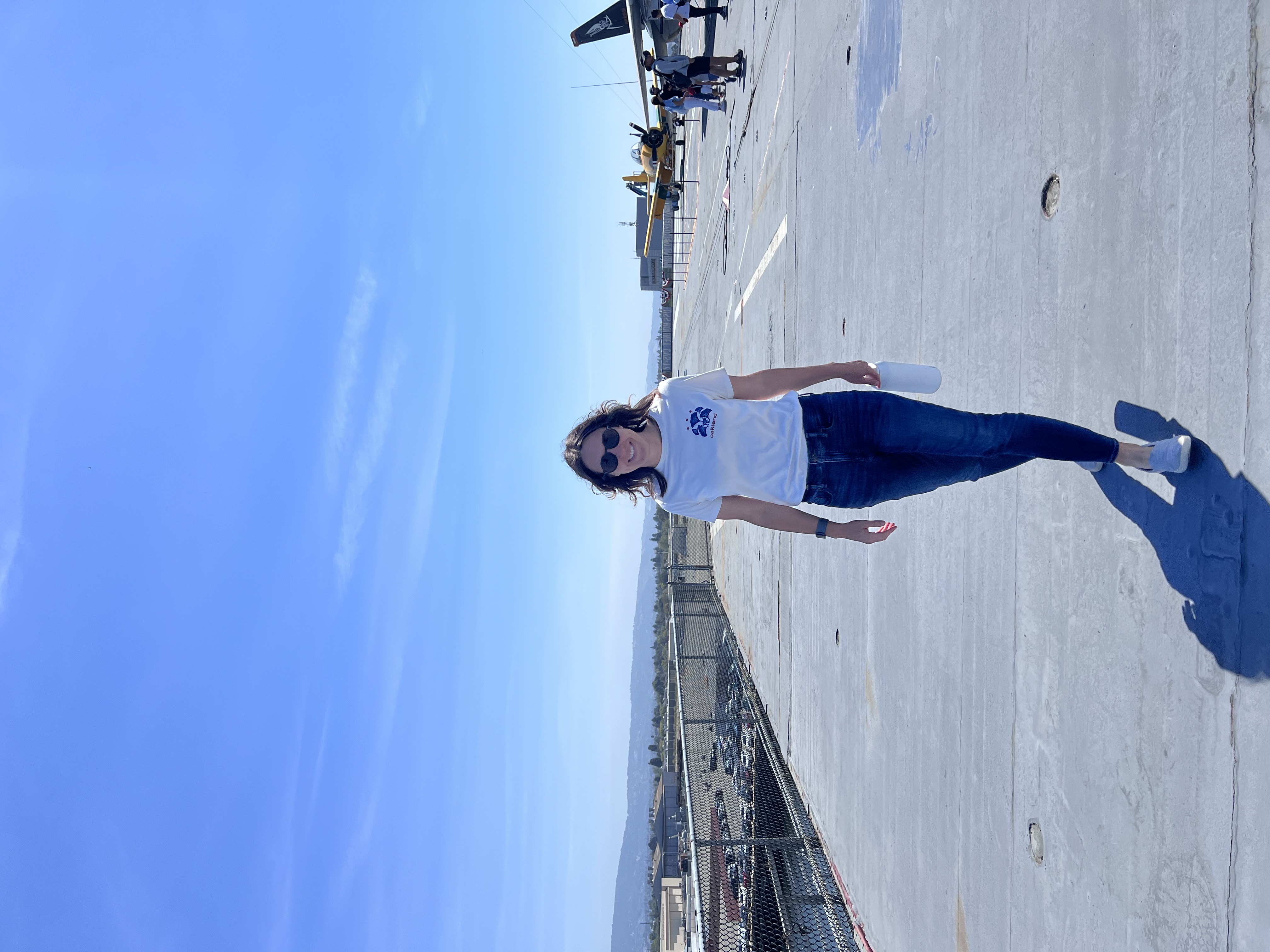 A woman in a white t-shirt and jeans walks along an airport runway or