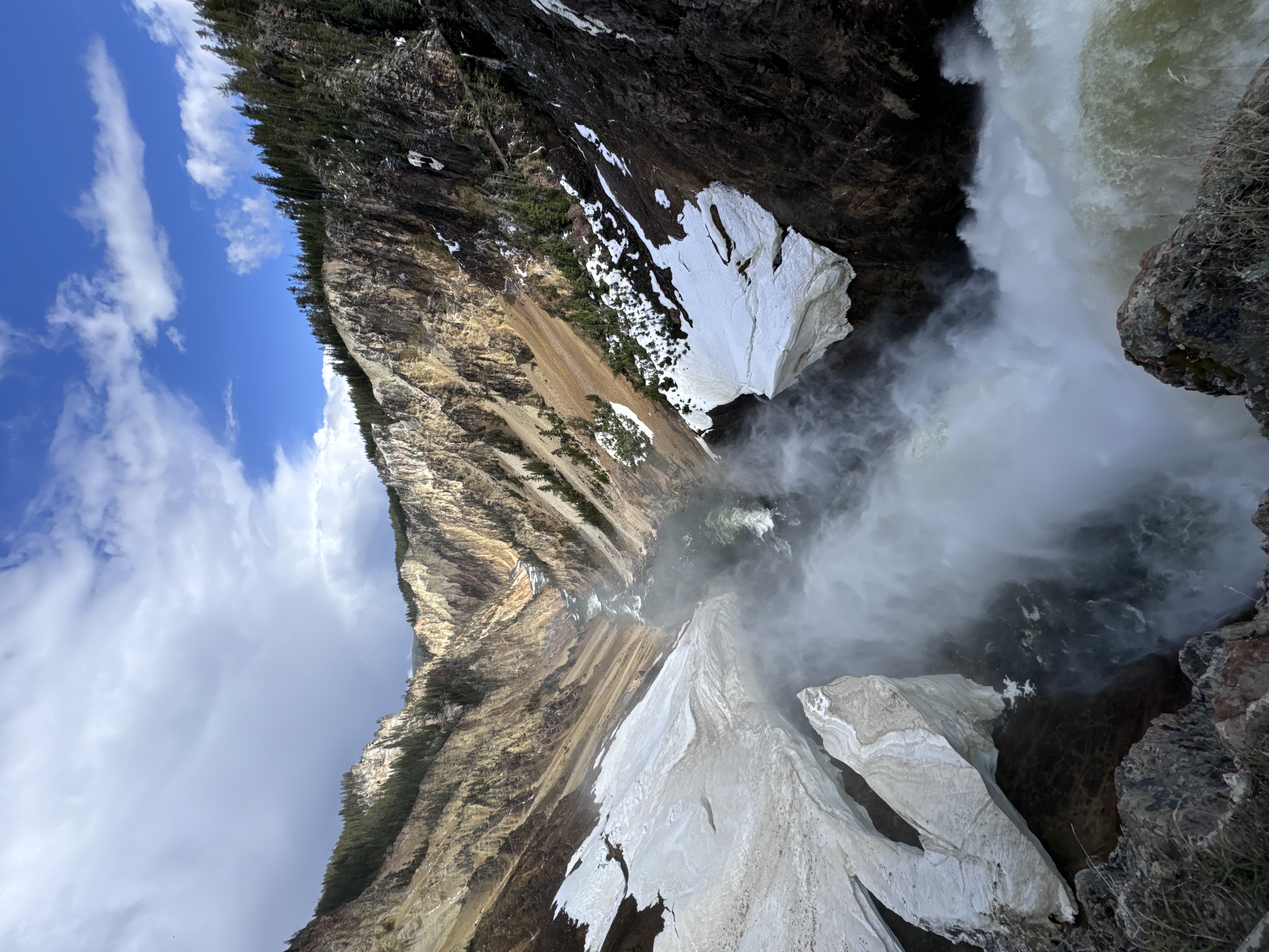 A powerful waterfall cascades down through a dramatic rocky canyon with