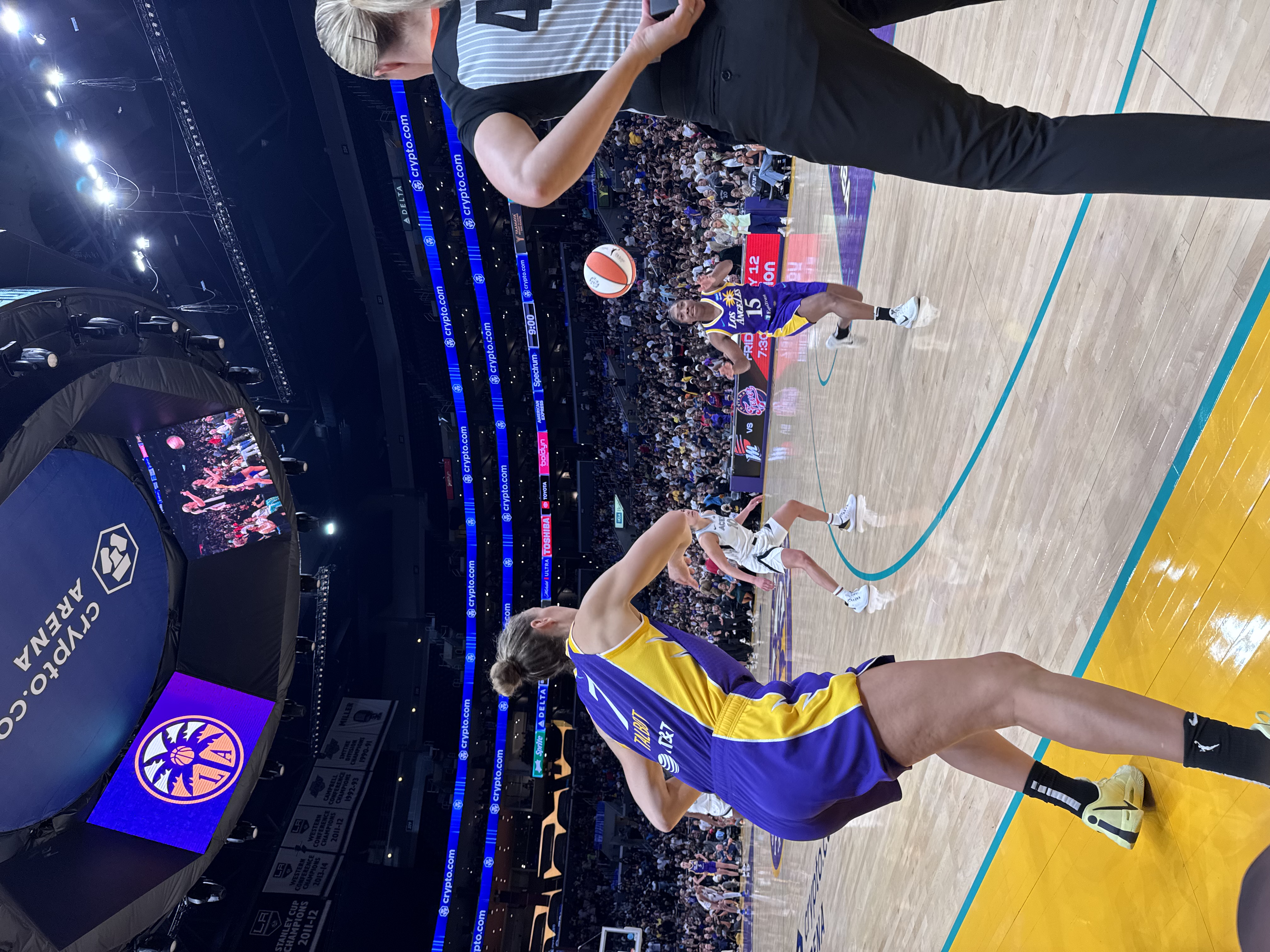 A WNBA basketball game in progress at a packed arena, with players in