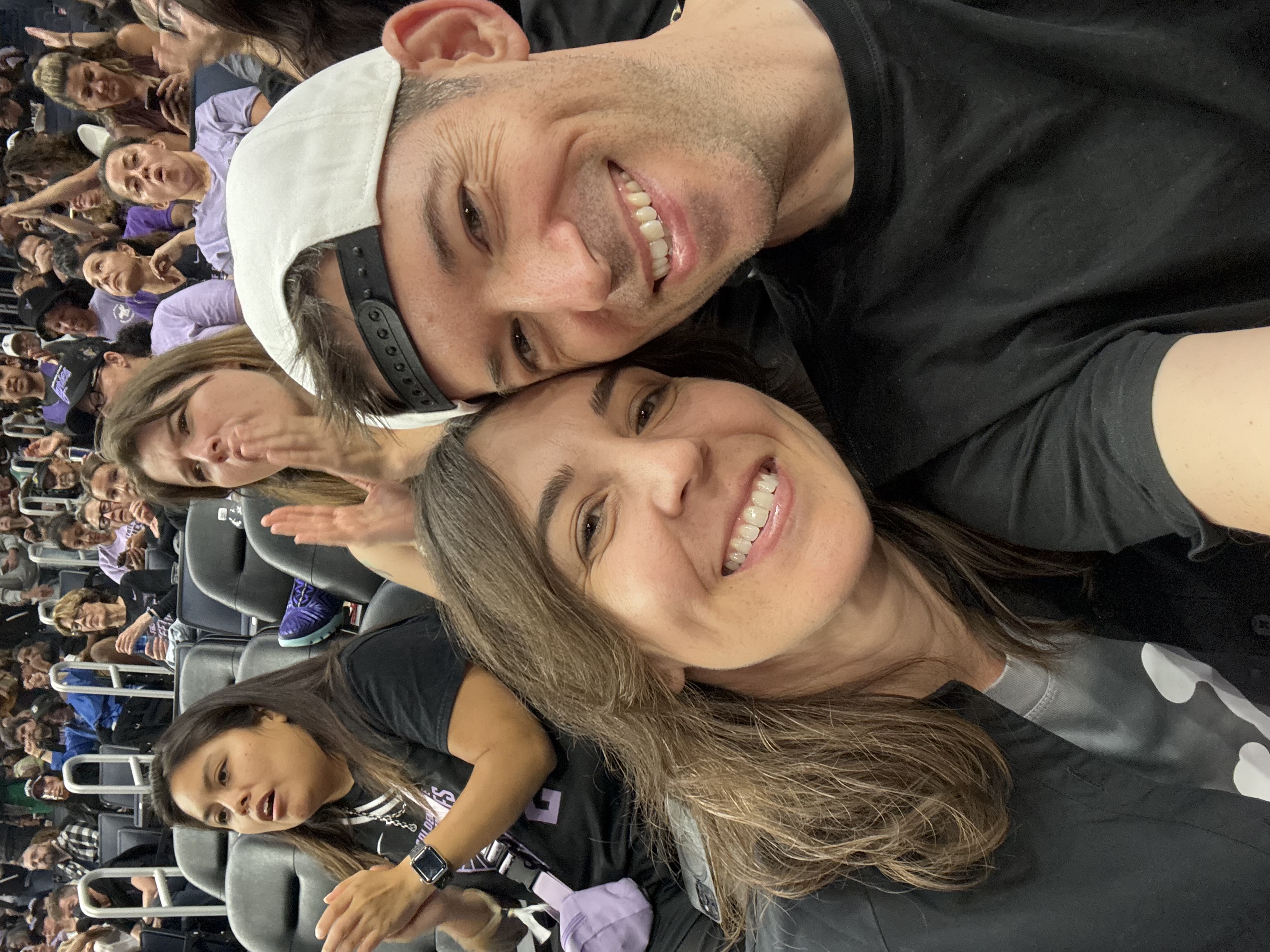 A smiling couple takes a selfie together at what appears to be a sporting