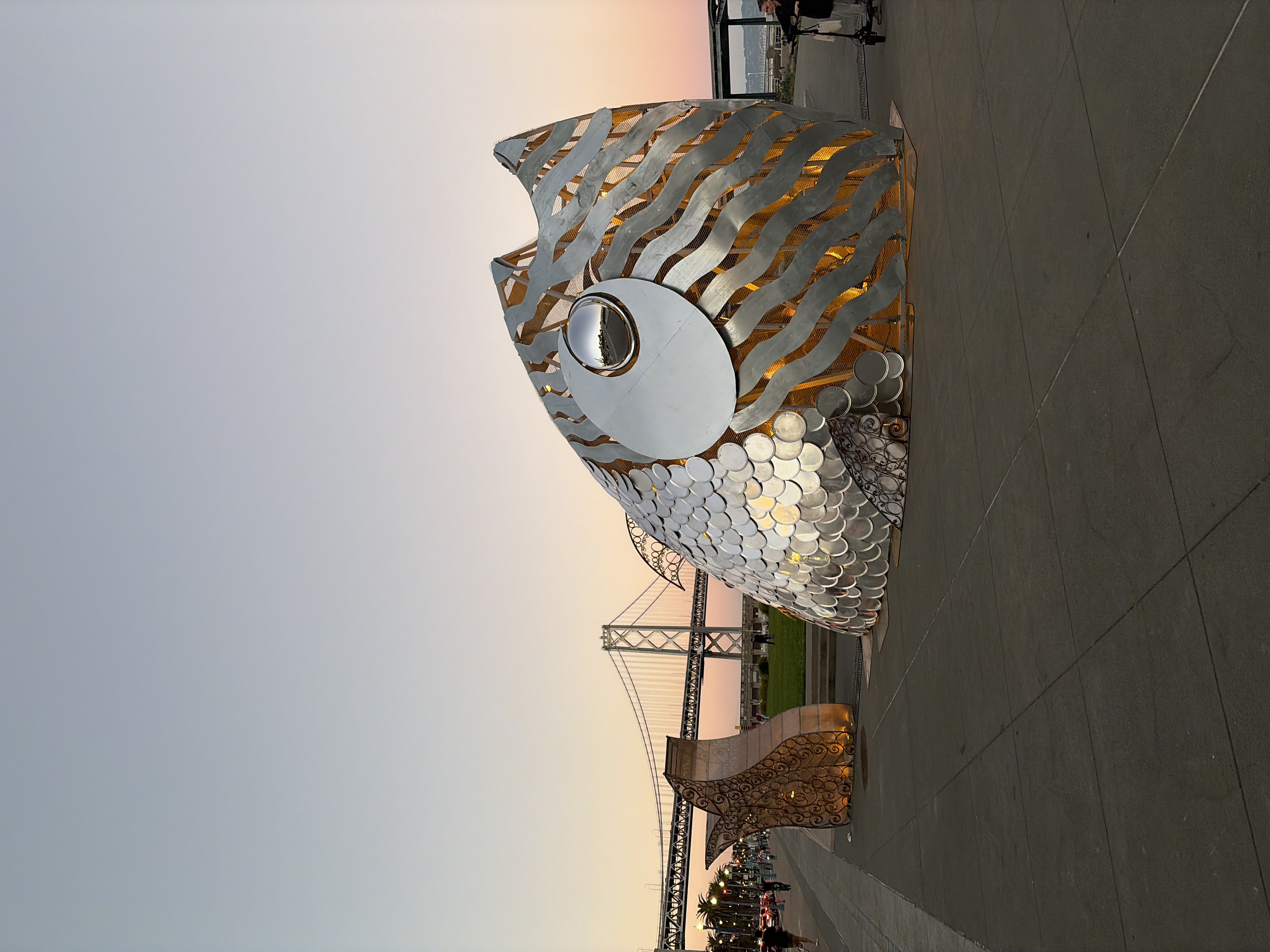 A large metallic fish sculpture with reflective scales and a circular eye