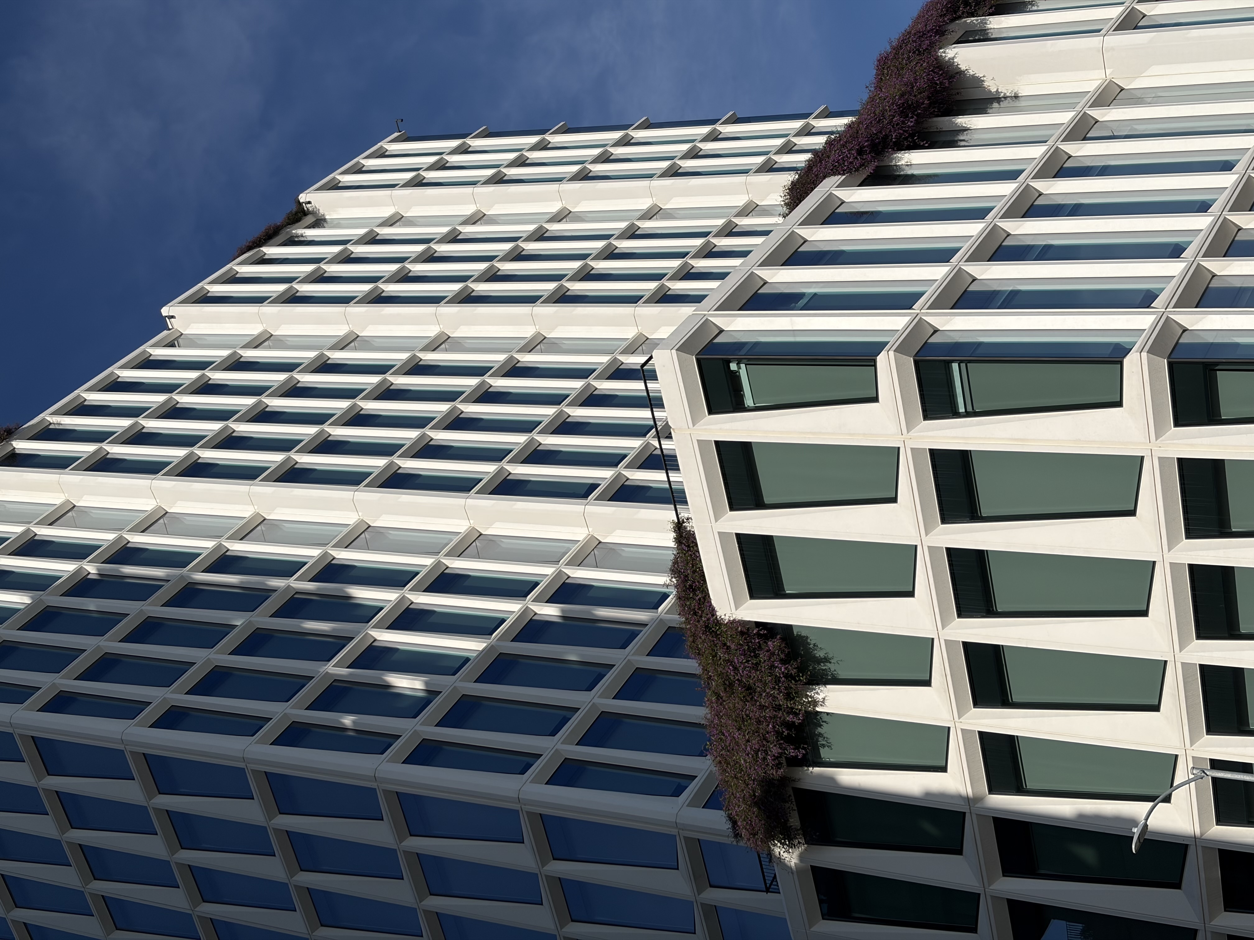 A modern white office building with a geometric glass facade features